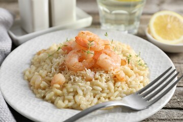 Delicious risotto with shrimps and cheese on wooden table, closeup