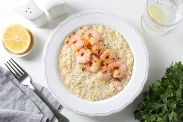 Delicious risotto with shrimps and cheese served on white table, top view