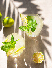 Two glasses with lime lemonade with mint and ice. Refreshing mojito cocktail with citrus fruits