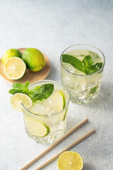 Two glasses lime cocktail with fresh citrus fruits  and paper tube  on a texture  background.