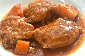 boiled chicken tight with carrot in swet red gravy sauce stew on plate 