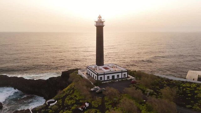 Aerial view of Faro de Punta Cumplida with beautiful sunset over the ocean and rocky coastline, Lomo Machin, Spain.
