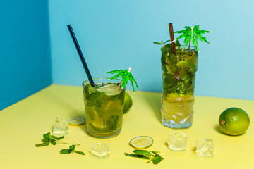 a shot glass with Mojito Cocktail with lime and limeade garnish on a yellow and blue background
