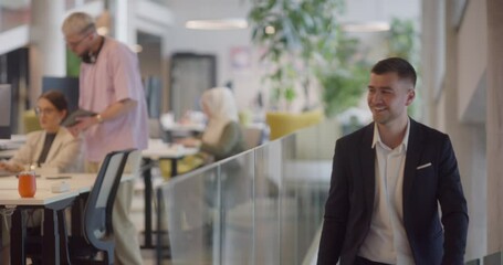 A director arrives at a large, modern office, where he joins his colleagues, exemplifying corporate leadership and teamwork in a dynamic workplace