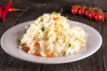 Cabbage salad on a white plate on a wooden background