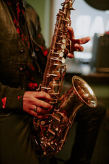 Vertical shot of unrecognizable Black musician playing saxophone during performance in local bar