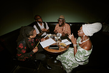 African American jazz band members spending evening in local bar working on new song, high angle...