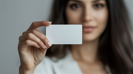 A beautiful woman holding up a business card on a gray background.