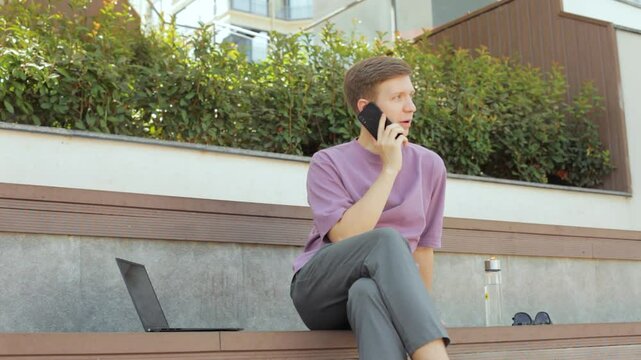 Young man speaking mobile phone on street. 