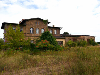 Ehemaliges Bahnhofsgebäude Haßleben mit verfallenen Bahnsteigen
