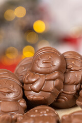 Chocolates in the shape of Christmas figures on the background of a flashing garland
