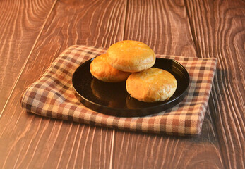 Chinese Pastry Mooncake baked round asian crispy cake with salted yellow bean paste cookies in black plate on wood table Traditional halal menu food sweet dessert for autumn festival cafe