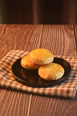 Chinese Pastry Mooncake baked round asian crispy cake with salted yellow red bean paste and eggs yolk in black plate on wood table Traditional halal menu food sweet dessert for autumn festival cafe