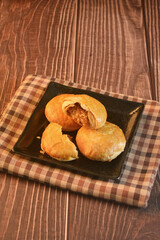 Chinese Pastry Mooncake baked round asian crispy cake with salted yellow red bean paste and eggs yolk in black plate on wood table Traditional halal menu food sweet dessert for autumn festival cafe
