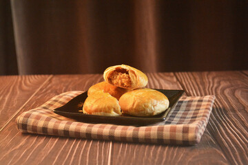 Chinese Pastry Mooncake baked round asian crispy cake with salted yellow red bean paste and eggs yolk in black plate on wood table Traditional halal menu food sweet dessert for autumn festival cafe
