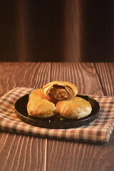 Chinese Pastry Mooncake baked round asian crispy cake with salted yellow red bean paste and eggs yolk in black plate on wood table Traditional halal menu food sweet dessert for autumn festival cafe