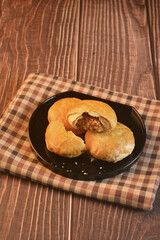 Chinese Pastry Mooncake baked round asian crispy cake with salted yellow red bean paste and eggs yolk in black plate on wood table Traditional halal menu food sweet dessert for autumn festival cafe