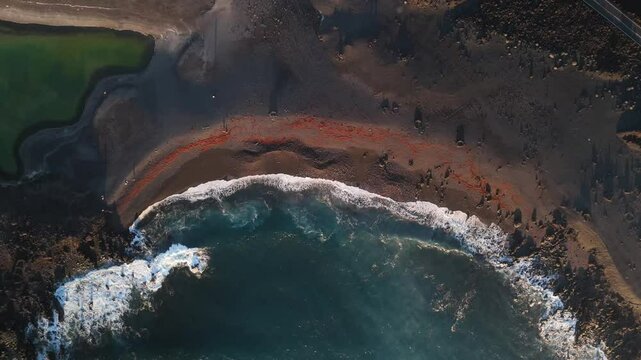 Aerial view of black sand beach and volcanic landscape with Volcan Bermeja and Tiny Charco Verde, El Golfo, Spain.