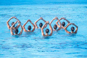 Synchronized swimmers team performing artistic swimming in the swimming pool