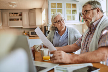 Senior couple reviewing documents together at kitchen table