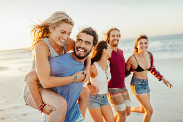 Friends laughing and having fun on the beach at sunset