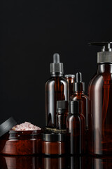 Collection of amber glass bottles arranged on a dark reflective surface, showcasing various shapes and sizes