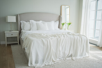 Stylish loft bedroom interior. Spacious design apartment with light walls large windows big bed. Clean modern decoration with elegant furniture in minimalist Scandinavian style