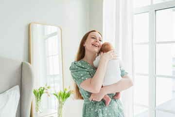 Happy family at home. Mother holding little toddler child daughter. Mom and baby girl relax playing having fun together at home. Mother hugs baby with love care. Mom of breast feeding baby