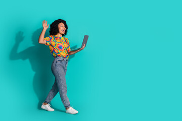 Full length photo of shiny attractive lady dressed retro t-shirt holding modern gadget walking waving hi empty space isolated blue color background