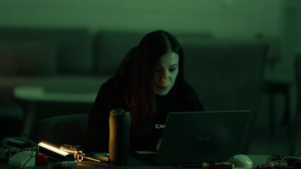 A beautiful young female programmer is enthusiastically working on a laptop. Girl hacker typing at the computer. 