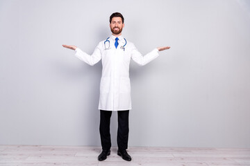 Full body portrait of experienced doctor man hold empty space wear white coat isolated on grey...