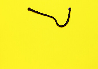 Close-up of yellow shopping bag with black handles, symbolizing the concept of shopping and retail. Promotion of sale period. Concept of shopping, Black Friday, Cyber Monday. Copy space for ad, text