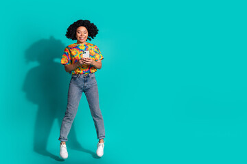 Full length photo of shiny attractive lady dressed retro t-shirt communicating gadget jumping high empty space isolated blue color background