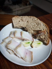 Close-up of a plate with lard, black bread, garlic and homemade cucumbers on a wooden table - Concept of traditional, organic homemade, Ukrainian, Slavic food.
