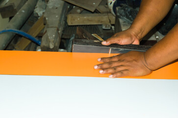 Photo of a carpenter tidying up the making of a wooden cabinet using wood shavings.