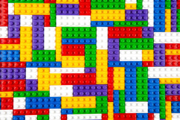 Abstract background texture of colored constructor blocks. Background of colorful plastic part of constructor. Pile of colored toy bricks.