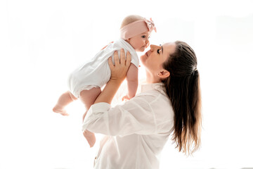 mom and baby hug and kiss at home on the bed in the bedroom, parental love and care, happy motherhood, mom with a baby in her arms, space for text