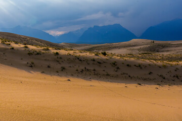 Dramatic desert dunes under sunbeams and cloudy sky