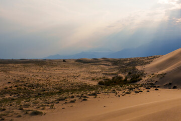 Dramatic desert dunes under sunbeams and cloudy sky