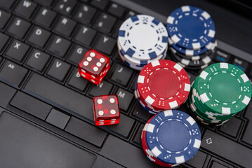 Colorful Poker Chips and Red Dice on Laptop Keyboard representing online gambling