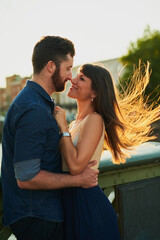 Couple, smile and hug with love in city for romantic outdoor date, vacation and holiday together. Man, woman and kiss in romance with connection at sunset for weekend adventure, embrace and marriage