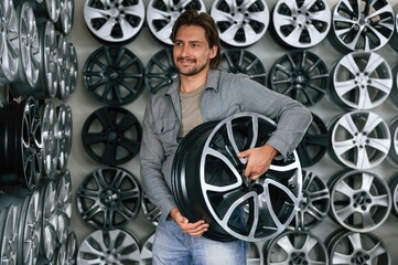 Many of the disks on walls. Man is in the tire fitting car service