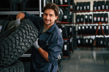 Professional worker is with wheel. Man is in the tire fitting car service