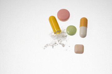 various pills and a broken capsule with spilled powder