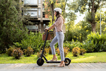 Woman in business suit riding electric scooter commuting to work.