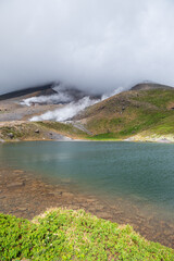 雲に覆われた火山のエメラルドグリーンの池