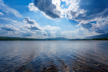 Calm lake with misty mountains and tree-lined shore