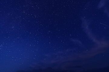 Obraz premium Star-filled night sky with a meteor streak and clouds