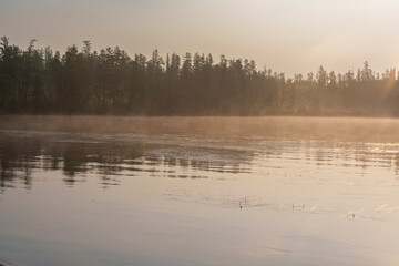 Fototapeta premium Misty morning lake with sunlight and forest silhouette