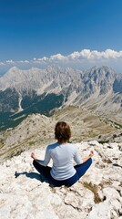 Naklejka premium A woman is meditating in the lotus position atop a mountain, surrounded by stunning clouds and peaks, embodying tranquility during a serene sunrise